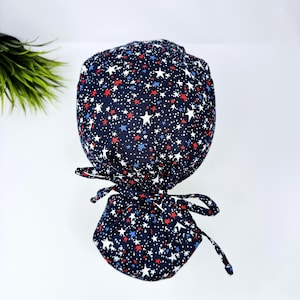ポニーテールの付いた星の手術用キャップ、独立記念日の手術用帽子。Paradise Caps のサテン裏地付き女性用スクラブキャップ。