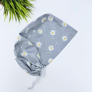 May include: A gray scrub hat with a white daisy print. The hat has a drawstring closure.