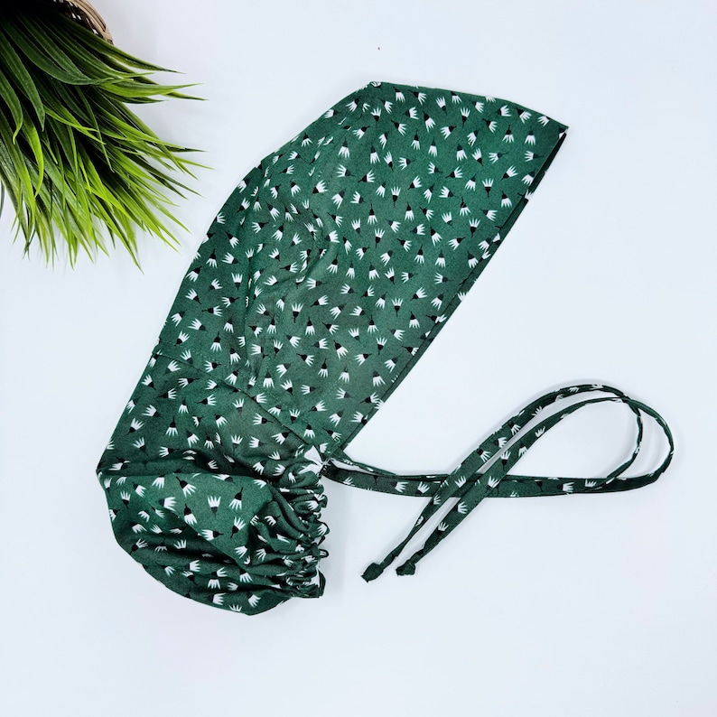 May include: A green surgical cap with a white floral pattern and adjustable ties.