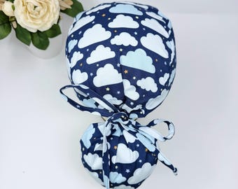 May include: A blue scrub hat with a white cloud and star pattern. The hat has a tie at the back.