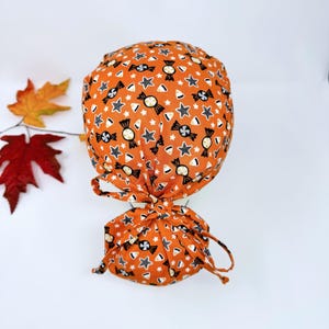 Halloween Ponytail scrub cap for women. Skull Surgical hat with satin lined option by Paradise Caps. Candy Corn on orange - print.