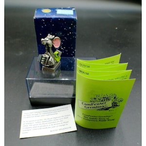 May include: A pewter figurine of a mouse with pink ears holding a green object, positioned on a clear plastic base in front of a blue box. A lime green folded pamphlet titled ComPewter Gremlins and a white information card are included.