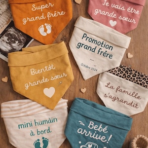 Peut inclure: Plusieurs bavoirs pour bébé de couleurs variées, chacun avec un message en français. Les phrases incluent "Super grand frère" et "Un Bébé arrive!" avec des empreintes de pas et des dessins de voiture.