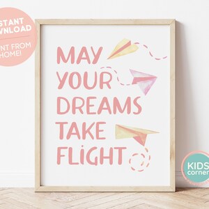 May include: Pink and yellow paper airplanes with a pink dashed line trail behind them. The text "May your dreams take flight" is written in pink letters.