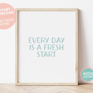 May include: A framed print with a light blue background and the text "EVERY DAY IS A FRESH START". The frame is made of wood and has a light brown finish. The print is surrounded by a white border.