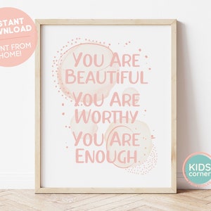 May include: A framed print with the words "YOU ARE BEAUTIFUL, YOU ARE WORTHY, YOU ARE ENOUGH" in pink lettering. The print has a light wood frame and is on a white background. The words are set against a watercolor-style pink background.