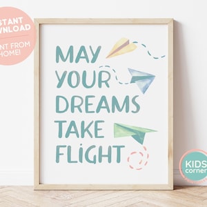 May include: A printable wall art print with the text "May your dreams take flight" in teal blue lettering. The print features three paper airplanes in yellow, blue, and green watercolor designs.