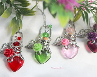 Könnte beinhalten: Fünf herzförmige Glasflaschen mit silbernen Metallkappen und Flügeln, jede mit einem anderen Farbglas und einer kleinen Rose an der Seite. Die Flaschen befinden sich auf einem weißen Hintergrund. -Viva's Jewelry-