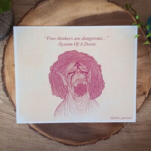 May include: A pink and white art print featuring a stylized illustration of a creature with large ears and an open mouth. The print includes the quote "Free thinkers are dangerous..." by System Of A Down, and the artist's signature.