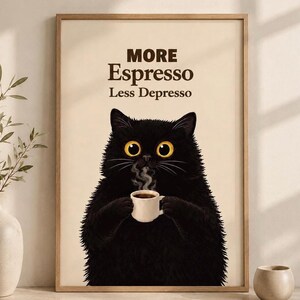 Könnte beinhalten: Ein gerahmtes Wandbild mit einer flauschigen schwarzen Katze mit großen gelben Augen, die eine kleine weiße Kaffeetasse mit aufsteigendem Dampf hält. Der Text MORE Espresso Less Depresso steht in dunkelbrauner Schrift auf cremefarbenem Grund.