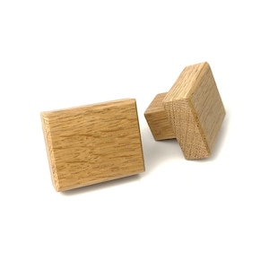May include: Two square wooden cabinet knobs with a light brown finish.