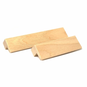 May include: Two wooden cabinet pulls with a light brown finish and a bevelled edge.