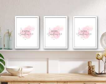 Peut inclure: Trois impressions encadrées blanches avec des fonds aquarelle roses et les mots "Foi 1 Corinthiens 13:13", "Espérance 1 Corinthiens 13:13" et "Amour 1 Corinthiens 13:13" en texte noir.
