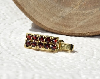 May include: A gold pendant with a rectangular design featuring a cluster of red garnet stones.