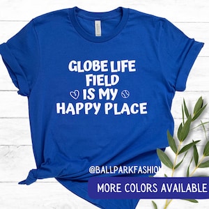 May include: Royal blue t-shirt with white text that reads "Globe Life Field is my happy place" with a heart and baseball graphic. The text "@ballparkfashion" is at the bottom of the shirt.