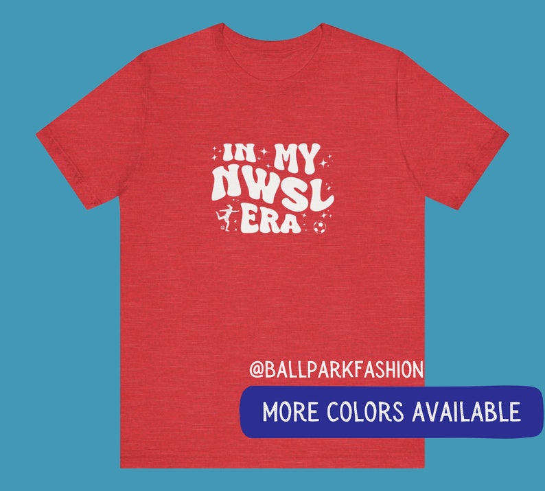 Pu&ograve; includere: T-shirt rosso melange con testo bianco che recita "In My NWSL Era" con un pallone da calcio e una silhouette di un calciatore. Il testo &egrave; in un font retr&ograve;. La parte inferiore della maglietta ha il testo "@ballparkfashion" e un pulsante che dice "Altri colori disponibili".