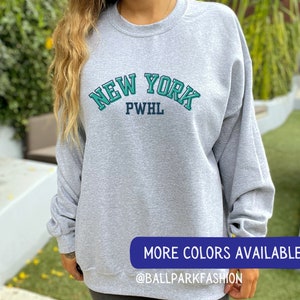 May include: Grey sweatshirt with a green and blue "NEW YORK PWHL" graphic.