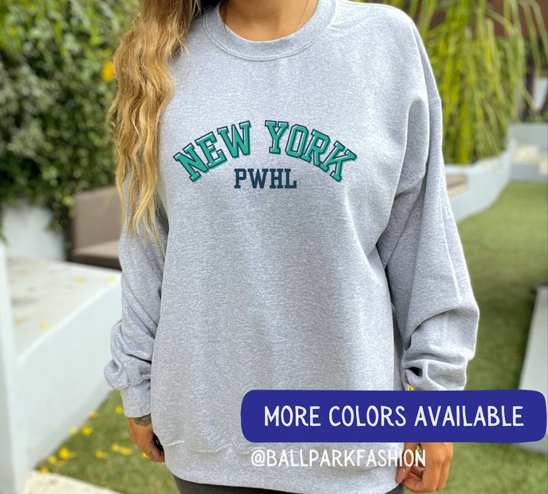 May include: Grey sweatshirt with a green and blue "NEW YORK PWHL" graphic.
