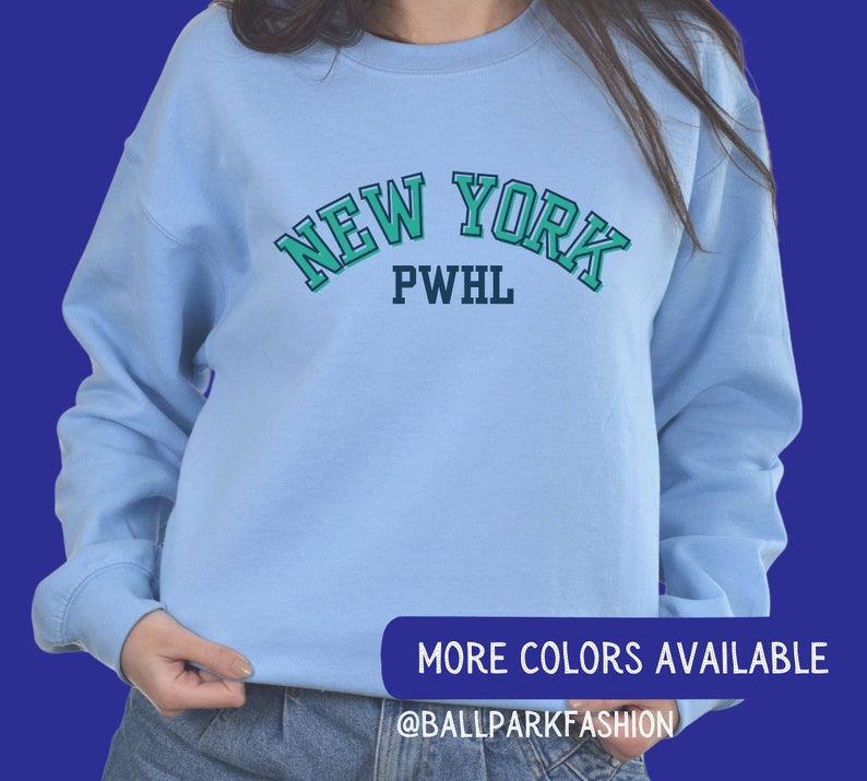 May include: Light blue sweatshirt with a green and white "NEW YORK PWHL" graphic.