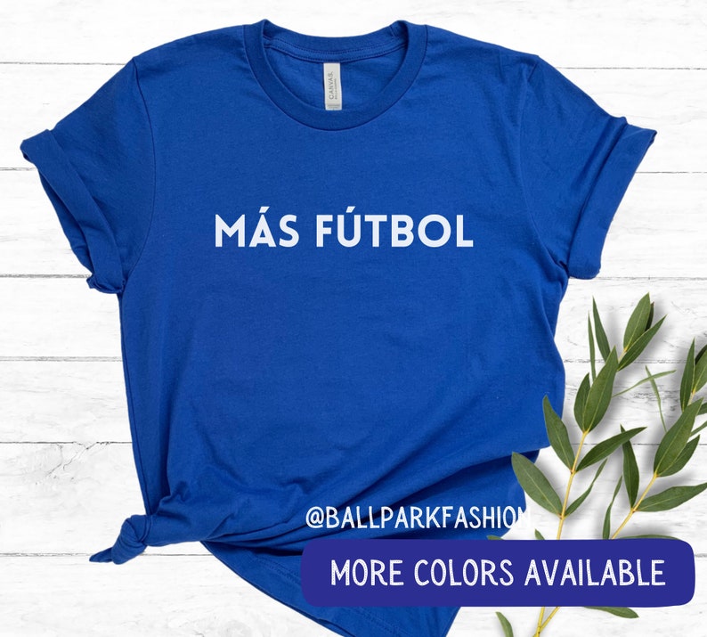 Puede incluir: Una camiseta azul real con el texto "M&Aacute;S F&Uacute;TBOL" en letras blancas. La camiseta est&aacute; hecha de un material suave y c&oacute;modo y es perfecta para el uso diario.  @BALLPARKFASHION M&Aacute;S COLORES DISPONIBLES