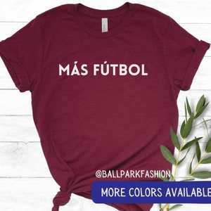 Puede incluir: Una camiseta de color burdeos con el texto "M&Aacute;S F&Uacute;TBOL" en letras blancas. La camiseta est&aacute; hecha de un material suave y c&oacute;modo y tiene un corte holgado. El texto est&aacute; centrado en la camiseta y es visible en la imagen. La camiseta est&aacute; disponible en otros colores.