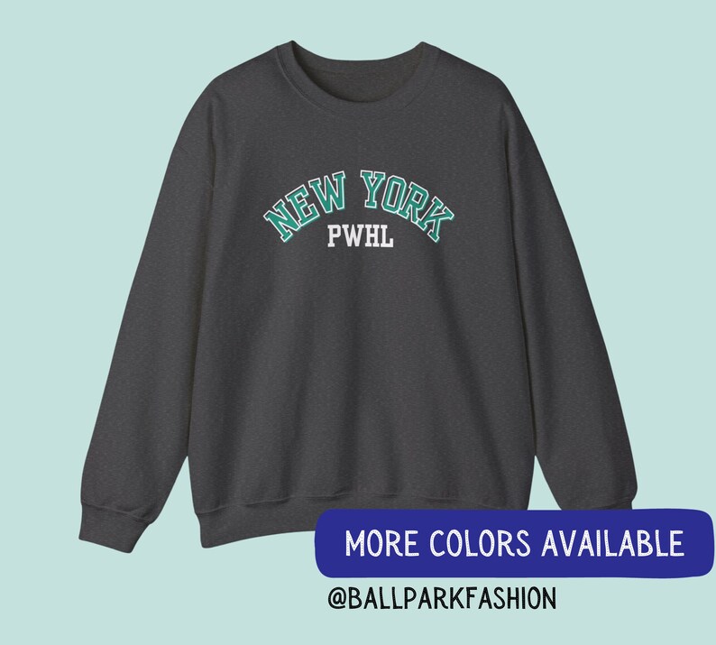 May include: A dark grey sweatshirt with a green and white "NEW YORK" graphic with the letters "PWHL" underneath. The text is in a collegiate style font. The sweatshirt has long sleeves and a crew neck.