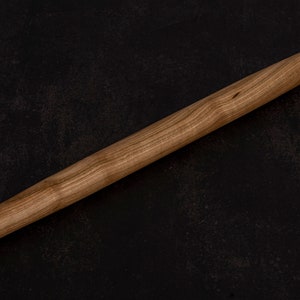Puede incluir: Un rodillo de madera con un acabado de madera natural. El rodillo mide aproximadamente 45 cm de largo y tiene una superficie lisa.