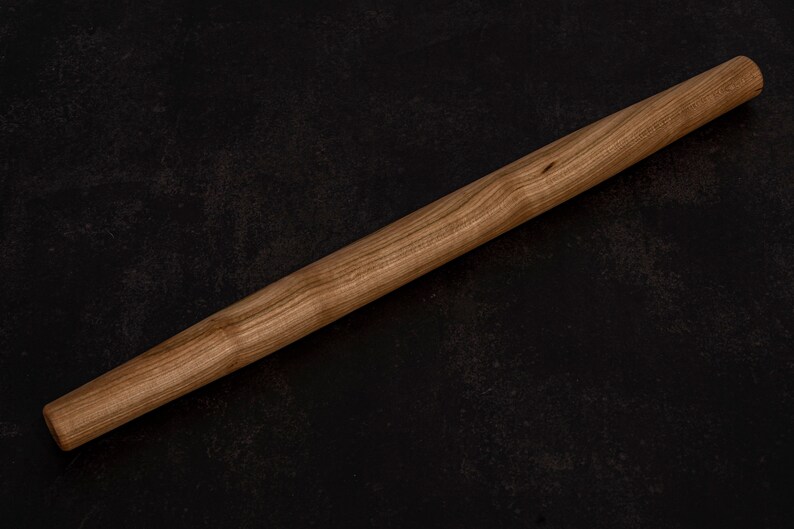 Puede incluir: Un rodillo de madera con un acabado de madera natural. El rodillo mide aproximadamente 45 cm de largo y tiene una superficie lisa.
