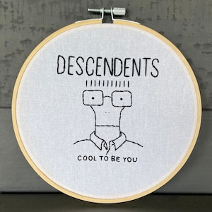 May include: Embroidered hoop art featuring a cartoon character with glasses and the text "DESCENDENTS COOL TO BE YOU".