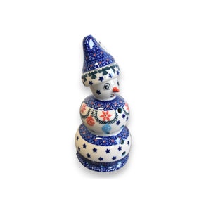 Może przedstawiać: Ceramiczna figurka bałwana z niebiesko-białym wzorzystym kapeluszem, ciałem i podstawą. Bałwan ma czerwony nos i niebiesko-biały wzorzysty szalik z czerwonymi i zielonymi ozdobami.