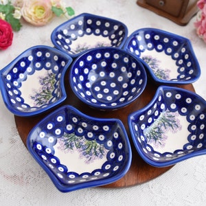 May include: A set of six blue and white ceramic serving dishes with a floral design. The dishes are arranged in a circle on a wooden tray.