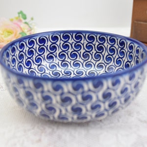 Peut inclure: Un bol en céramique blanche avec un motif de tourbillon bleu et blanc. Le bol est vide et a une finition brillante.