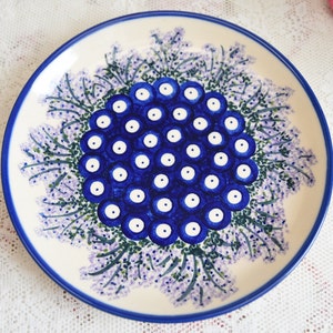 Könnte beinhalten: Ein weißer Keramikteller mit einem blauen und weißen Blumendesign. Die Mitte des Tellers zeigt eine Ansammlung von blauen und weißen Kreisen.