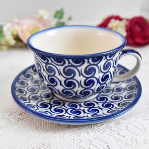 May include: A blue and white ceramic teacup and saucer set with a swirling pattern. The cup and saucer are both decorated with a repeating pattern of blue swirls on a white background.