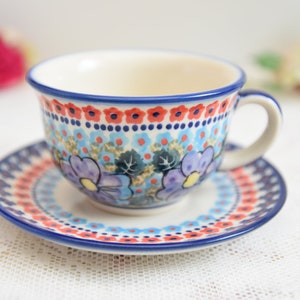 May include: A blue and white teacup and saucer set with a floral pattern. The cup and saucer are decorated with red, blue, and yellow flowers.
