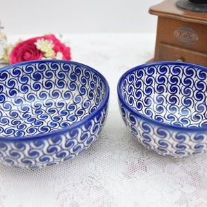 Pode incluir: Duas tigelas de cerâmica com um padrão de redemoinho azul e branco. As tigelas têm uma borda azul escura e um interior branco com um design de redemoinho azul repetido. As tigelas são provavelmente para servir comida.