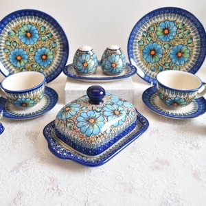 Könnte beinhalten: Ein blaues und weißes Teeservice mit Blumenmuster mit zwei Tassen, Untertassen und Tellern, einer Butterdose, zwei Salz- und Pfefferstreuern und zwei Eierbechern.