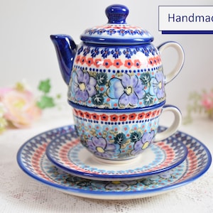 Op de afbeelding: Een blauwe en witte bloemen theeset met een theepot, kop en schotel. De set is handgemaakt en heeft een delicaat bloemenpatroon.