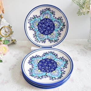 Puede incluir: Cuatro platos de cena de cerámica azul y blanca con un diseño floral. Los platos están apilados uno encima del otro.