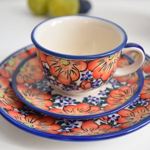 May include: A set of three ceramic plates with a floral design. The plates are decorated with orange, blue, and green flowers. The largest plate is 9 inches in diameter.