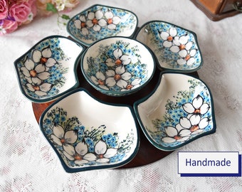 May include: A wooden serving tray with six ceramic bowls. The bowls are decorated with a floral pattern of white flowers with blue and green accents. The tray is handmade and has a dark brown finish.