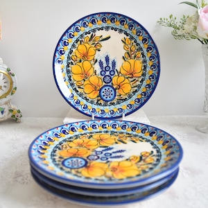 Könnte beinhalten: Ein Satz von vier blauen und weißen Keramiktellern mit gelbem Blumendesign. Die Teller sind übereinander gestapelt.