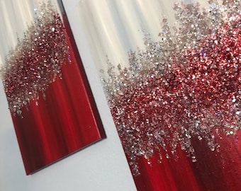 May include: Two red and white canvas paintings with a glittery texture. The paintings are hung on a white wall.
