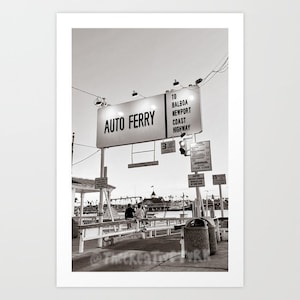 May include: A black and white photo of a sign that reads "Auto Ferry" with an arrow pointing to the right. The sign also says "To Balboa, Newport Coast Highway".