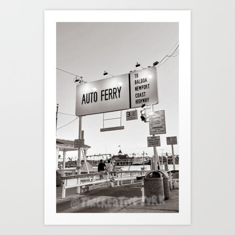May include: A black and white photo of a sign that reads "Auto Ferry" with an arrow pointing to the right. The sign also says "To Balboa, Newport Coast Highway".