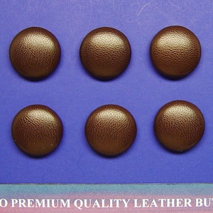 May include: Six brown leather buttons with a textured surface.  The buttons are arranged in two rows of three.