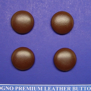 May include: Four brown leather buttons with a textured surface. The buttons are arranged in a square pattern on a blue background.
