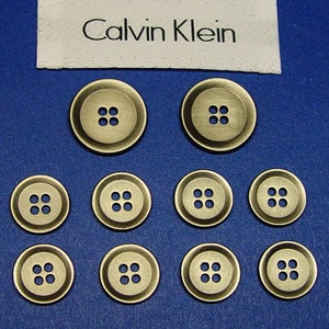 10 botones de reemplazo de metal plateado oscuro Calvin Klein, coso de 4 agujeros a través, buen estado utilizado.