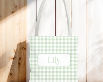 May include: A light green and white gingham tote bag with a white handle. The bag features the name "Lily" in a white rectangular frame. The bag is made of fabric and is suitable for carrying items.