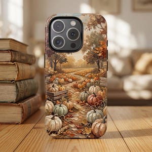May include: A smartphone case featuring an oil painting style illustration of a pumpkin patch in autumn. The design displays numerous pumpkins in shades of orange, white, and green scattered along a path surrounded by trees with fall foliage.